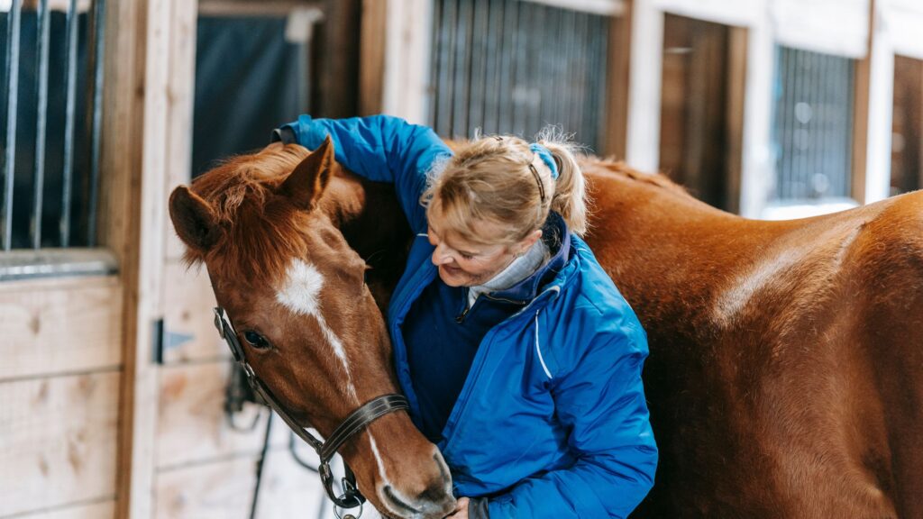 old woman patting her horse for companionship .