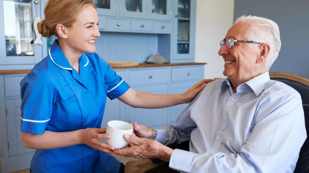 carer giving elderly man a cup of tea